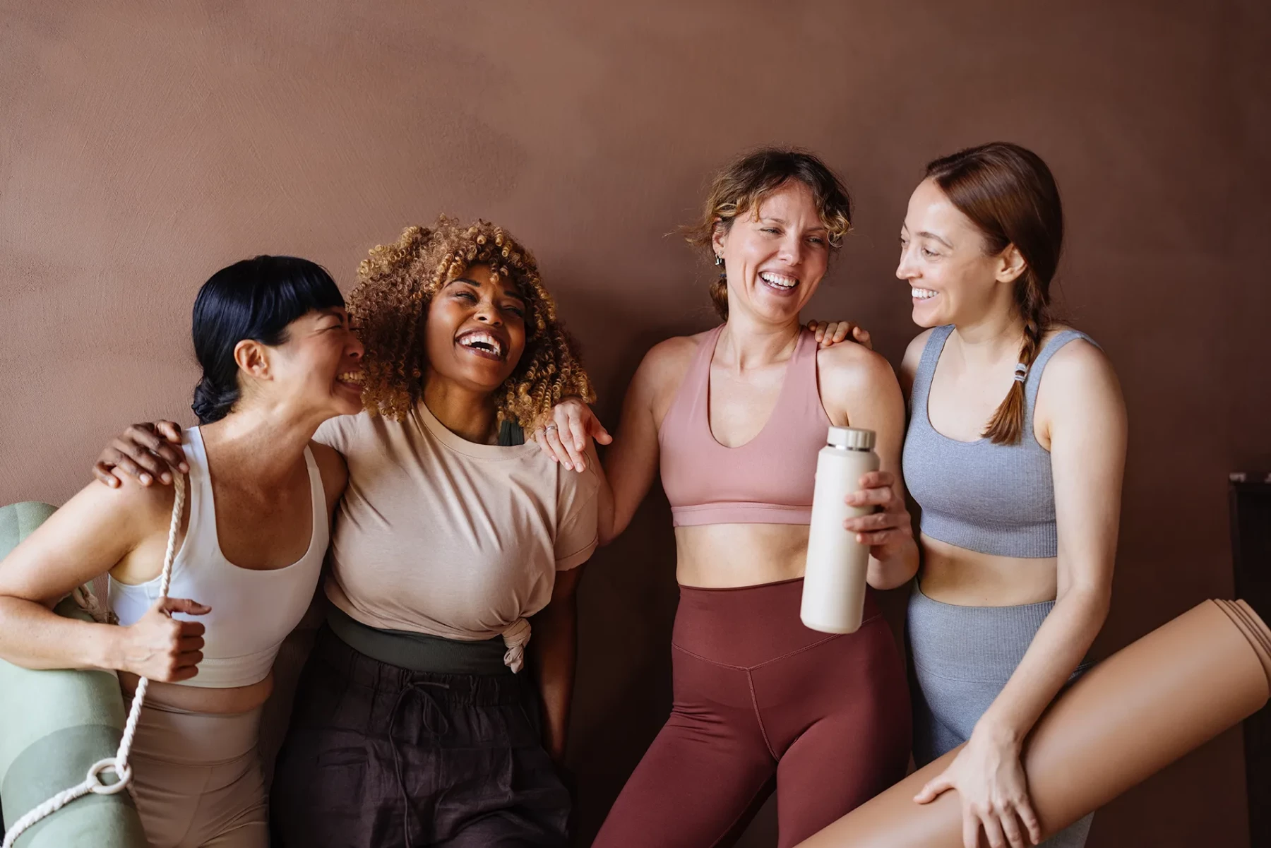 Four women in activewear enjoying time together after exercise.